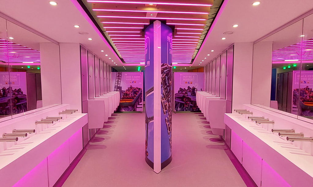 A washroom with pink lighting and two green toilet occupancy sensor lights above each cubicle.